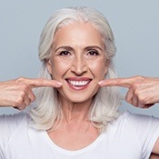 Older woman pointing to healthy smile