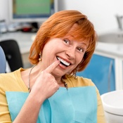 Senior woman pointing to implant denture