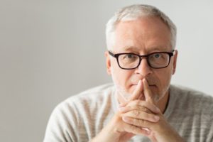 An older man holding his hands to his mouth.