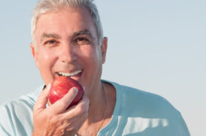 man smiling holding apple